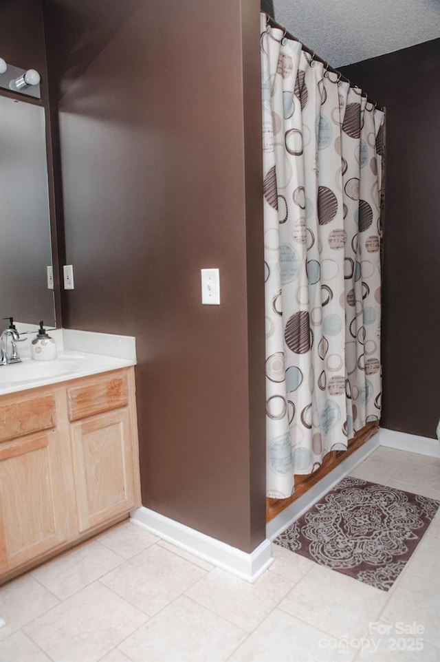 bathroom featuring baseboards, tile patterned floors, curtained shower, a textured ceiling, and vanity