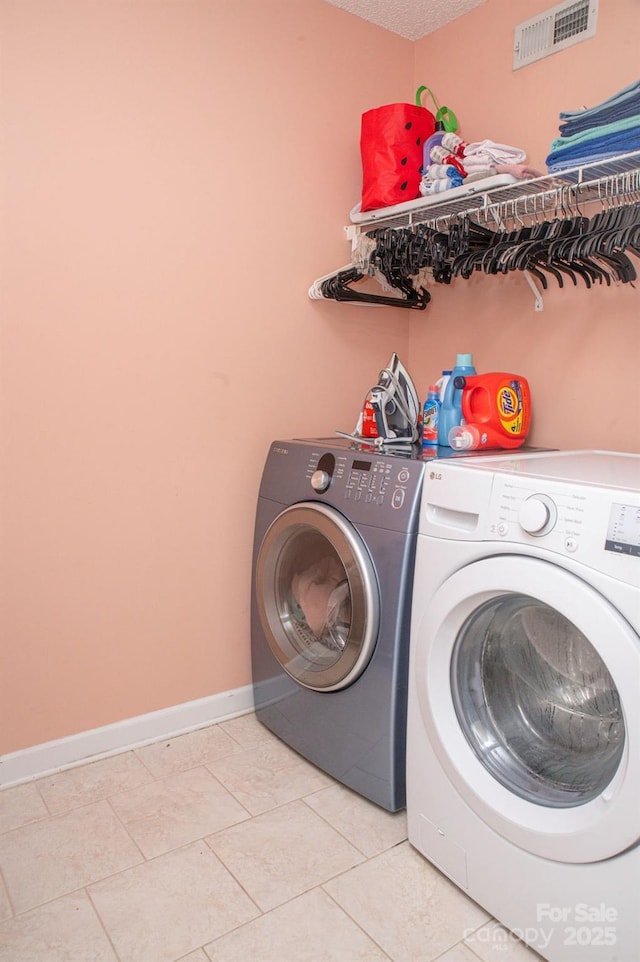 laundry area with visible vents, washing machine and dryer, a textured ceiling, laundry area, and baseboards