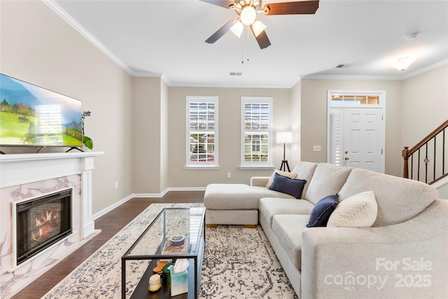 living area with baseboards, a fireplace, ornamental molding, and wood finished floors