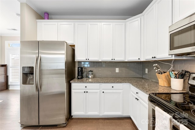 kitchen with stainless steel appliances, ornamental molding, stone countertops, and white cabinetry