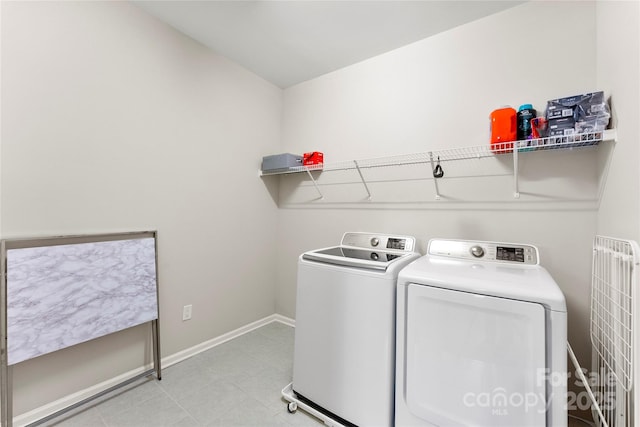 clothes washing area with washing machine and dryer, laundry area, and baseboards