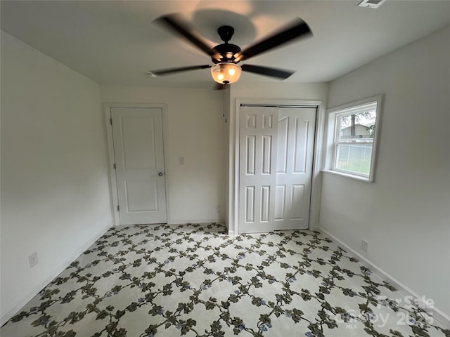 unfurnished bedroom featuring a ceiling fan, baseboards, light floors, and a closet