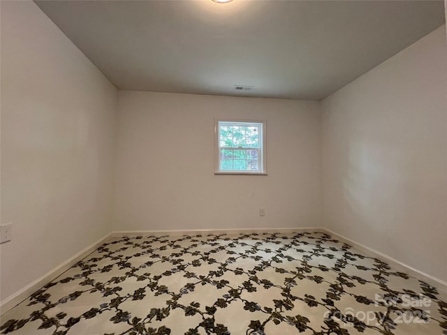 empty room with carpet, visible vents, and baseboards