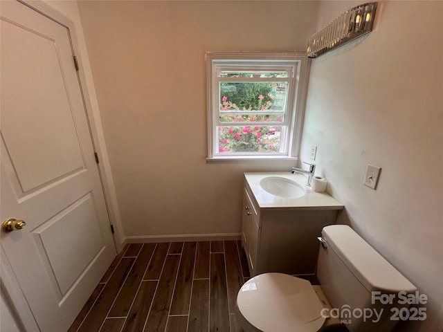 bathroom with baseboards, vanity, toilet, and wood finished floors