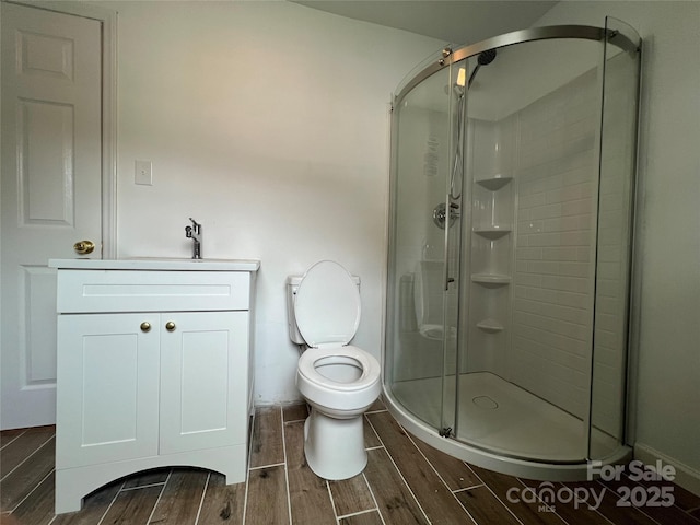 full bath with toilet, a shower stall, vanity, and wood finish floors