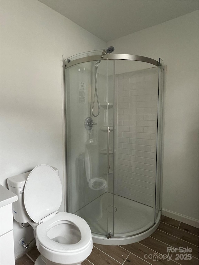 bathroom with a stall shower, vanity, toilet, and wood tiled floor