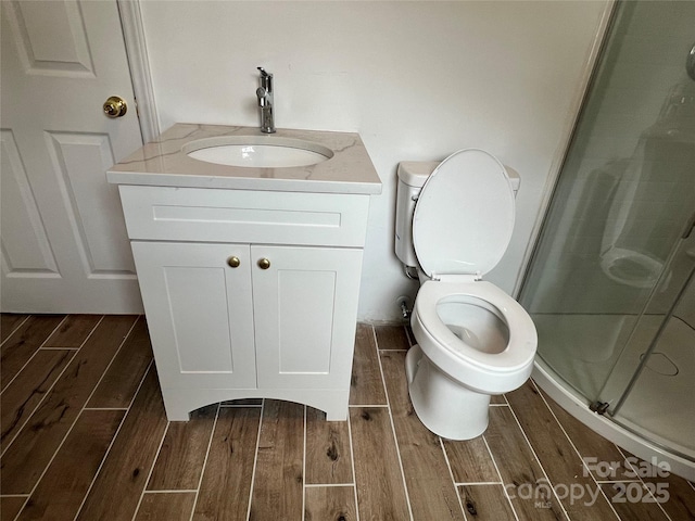 bathroom with toilet, a shower stall, vanity, and wood tiled floor