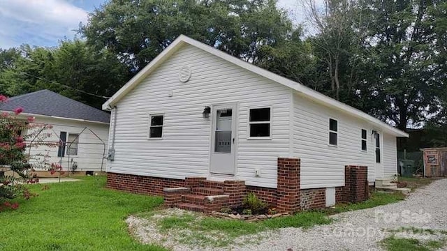 rear view of property with entry steps and a yard