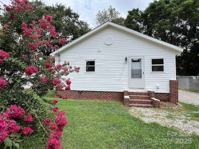 view of front of house with entry steps, fence, and a front lawn