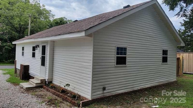 view of side of home with entry steps and fence