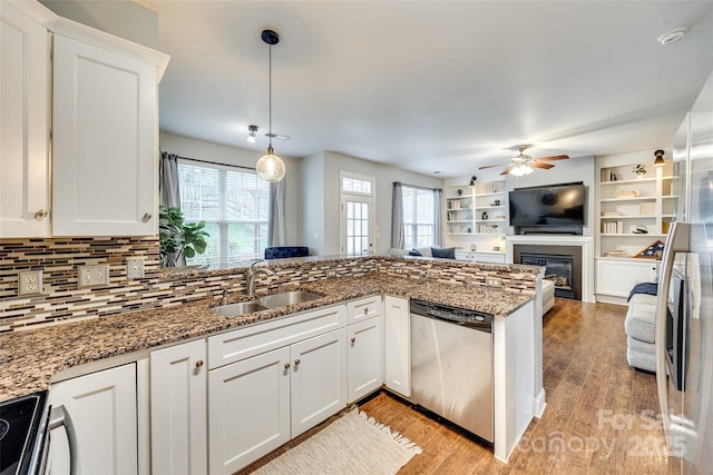 kitchen with stainless steel appliances, a sink, white cabinets, open floor plan, and light wood-type flooring