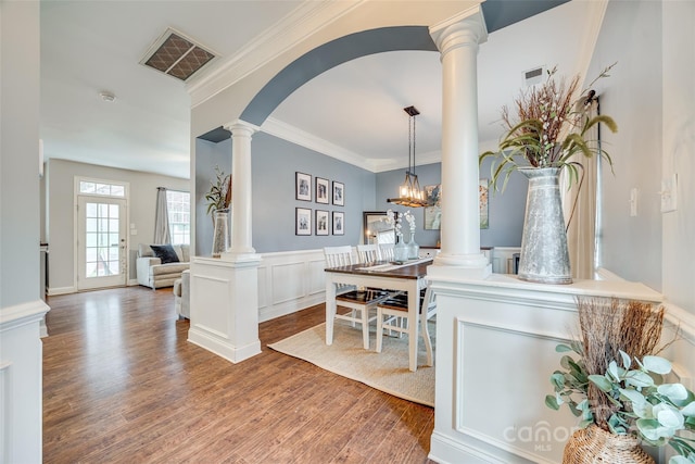 entryway with crown molding, decorative columns, visible vents, wainscoting, and wood finished floors