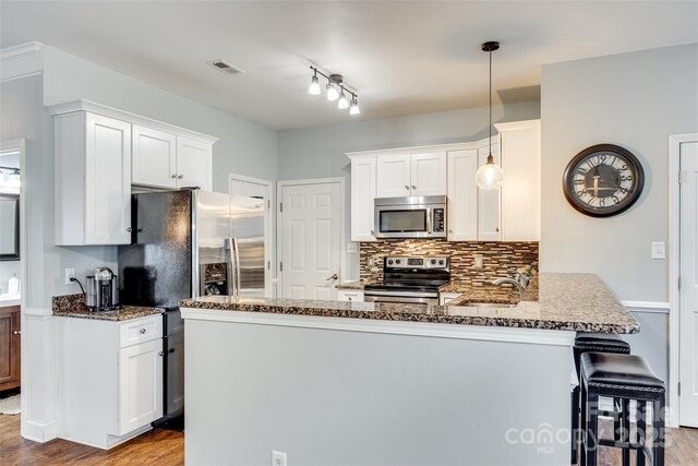 kitchen featuring tasteful backsplash, visible vents, appliances with stainless steel finishes, a sink, and a peninsula