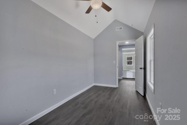 unfurnished room with dark wood-style floors, vaulted ceiling, visible vents, and baseboards