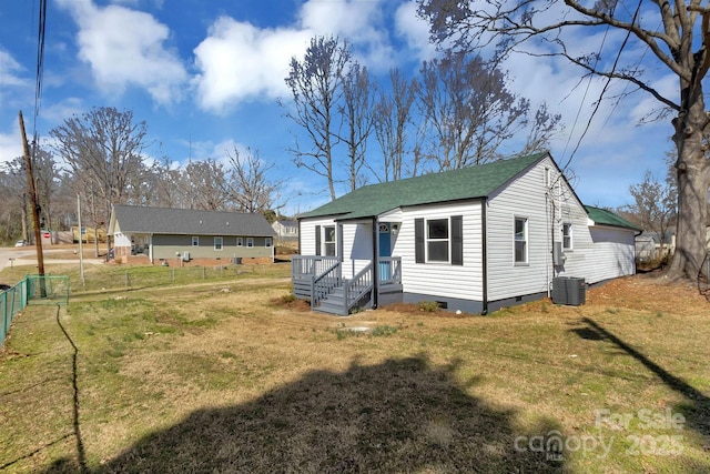 rear view of house featuring crawl space, a shingled roof, fence, and a lawn