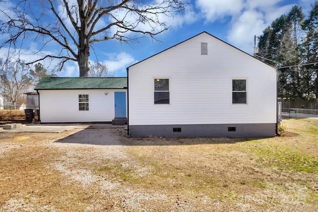 rear view of house with entry steps, crawl space, roof with shingles, and a yard