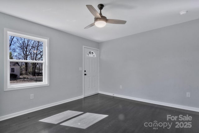 spare room with ceiling fan, baseboards, and dark wood-type flooring