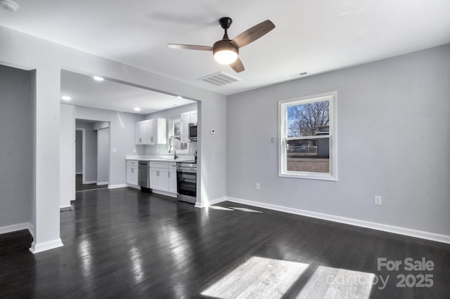 unfurnished living room featuring dark wood-type flooring, visible vents, and baseboards