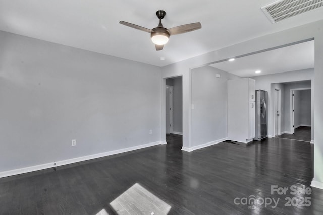 spare room with ceiling fan, dark wood-type flooring, visible vents, and baseboards