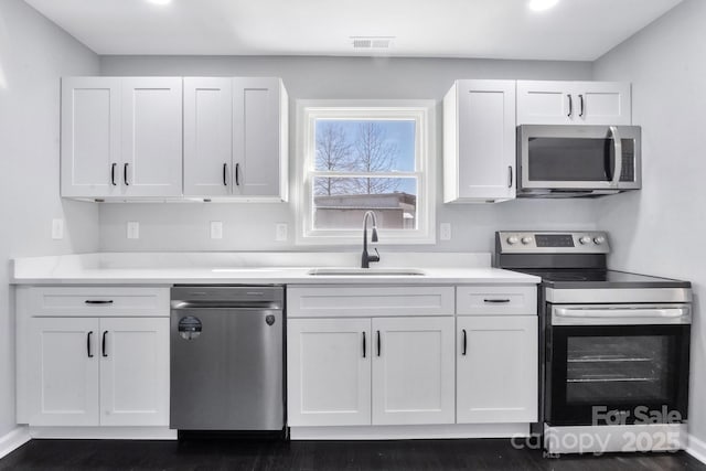 kitchen featuring light countertops, appliances with stainless steel finishes, a sink, and white cabinetry