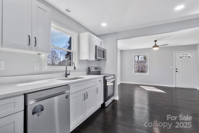 kitchen with light countertops, appliances with stainless steel finishes, a sink, and white cabinets