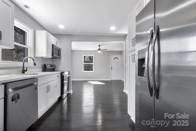 kitchen with baseboards, white cabinets, light countertops, appliances with stainless steel finishes, and dark wood finished floors