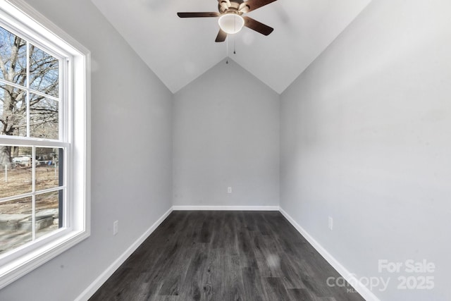 unfurnished room featuring lofted ceiling, baseboards, dark wood-style flooring, and a wealth of natural light