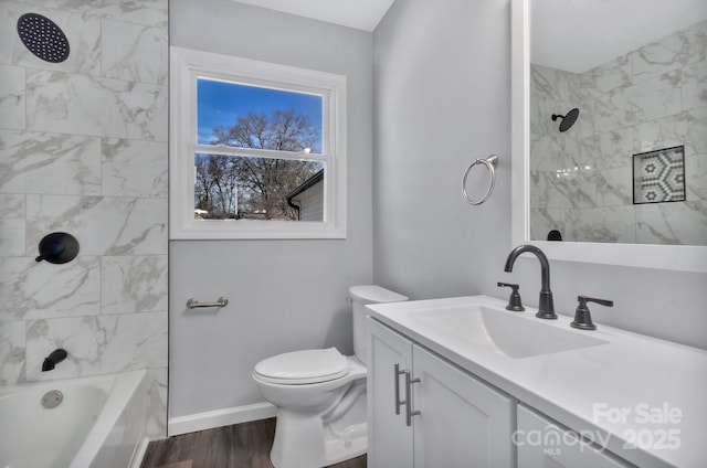 bathroom with baseboards, toilet, wood finished floors, vanity, and washtub / shower combination