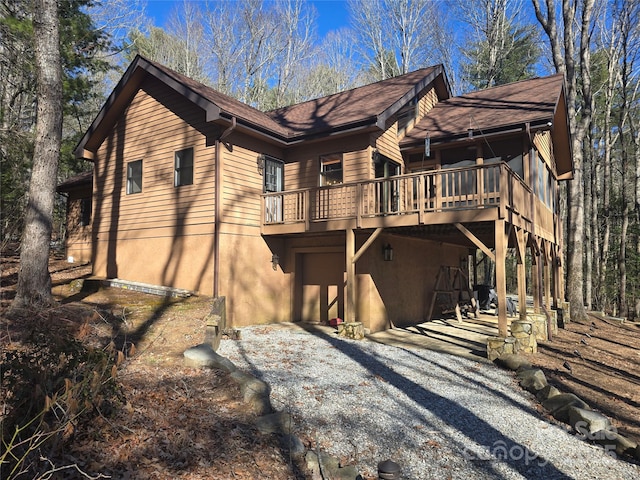 view of home's exterior featuring gravel driveway, an attached garage, and a deck