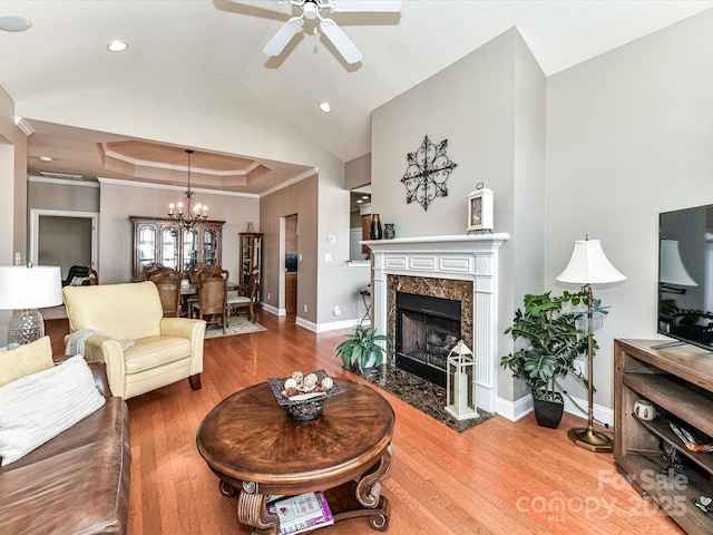 living room featuring a fireplace, vaulted ceiling, baseboards, and wood finished floors