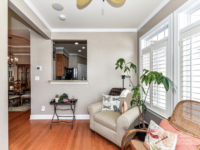 sitting room featuring a notable chandelier, crown molding, baseboards, and wood finished floors