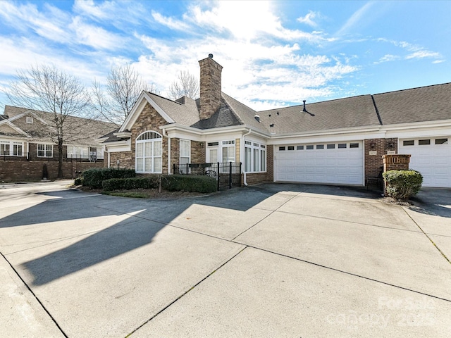 view of front of property with driveway, a garage, stone siding, a chimney, and fence