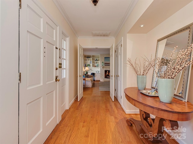 hallway featuring ornamental molding, visible vents, light wood-style flooring, and baseboards