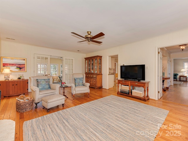 living room with ceiling fan, hardwood / wood-style floors, ornamental molding, and visible vents