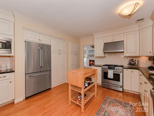 kitchen featuring visible vents, white cabinets, stainless steel appliances, light wood-type flooring, and under cabinet range hood