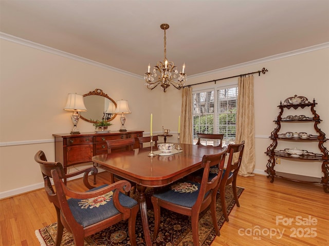 dining room with baseboards, ornamental molding, an inviting chandelier, and light wood-style floors