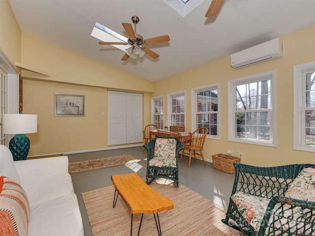 living room featuring ceiling fan, an AC wall unit, vaulted ceiling with skylight, and baseboards