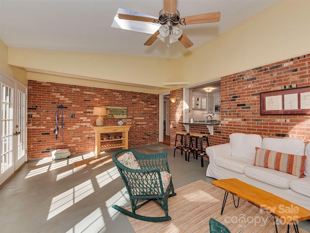 living area with french doors, ceiling fan, and brick wall