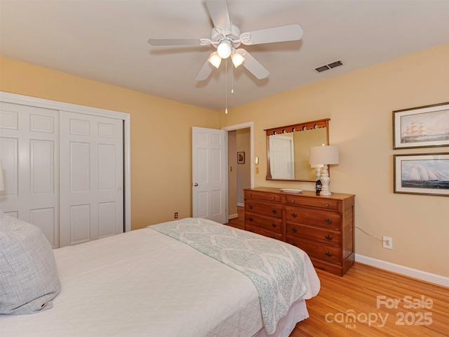 bedroom featuring baseboards, visible vents, ceiling fan, wood finished floors, and a closet