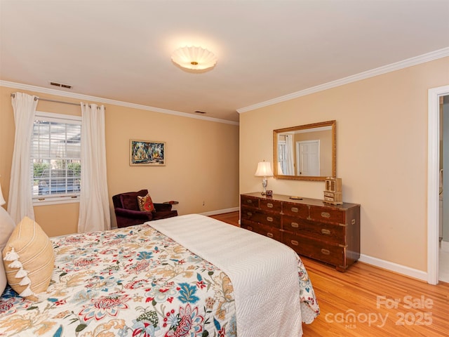 bedroom with baseboards, light wood finished floors, visible vents, and crown molding