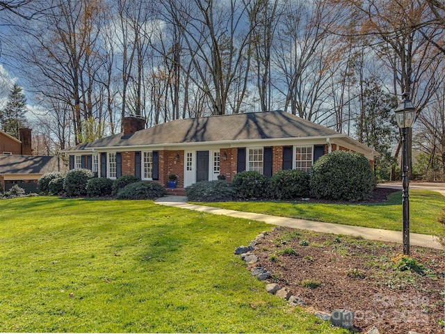 single story home with a front lawn, a chimney, and brick siding