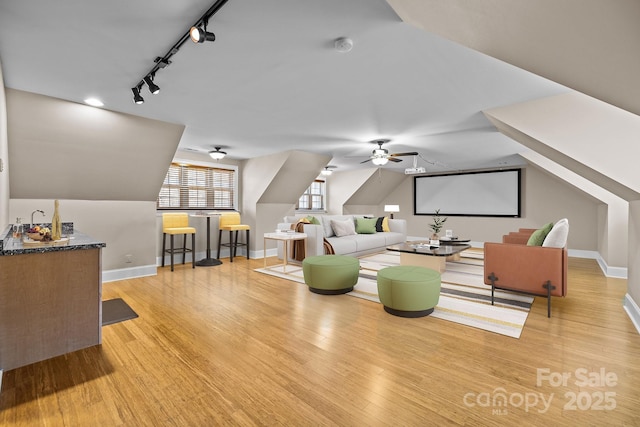 living room featuring lofted ceiling, ceiling fan, baseboards, and wood finished floors