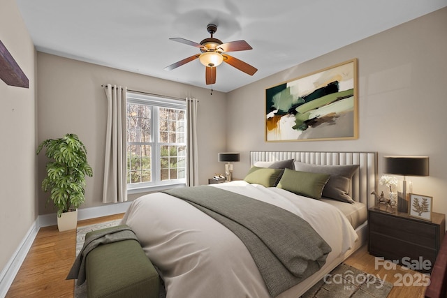 bedroom with ceiling fan, wood finished floors, and baseboards