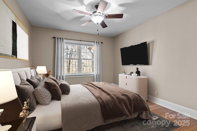 bedroom with a ceiling fan, baseboards, and wood finished floors