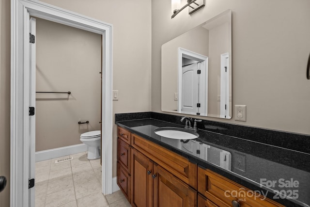 bathroom with toilet, tile patterned floors, baseboards, and vanity