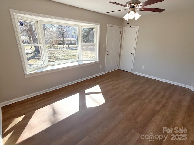 unfurnished room with dark wood finished floors, baseboards, and ceiling fan