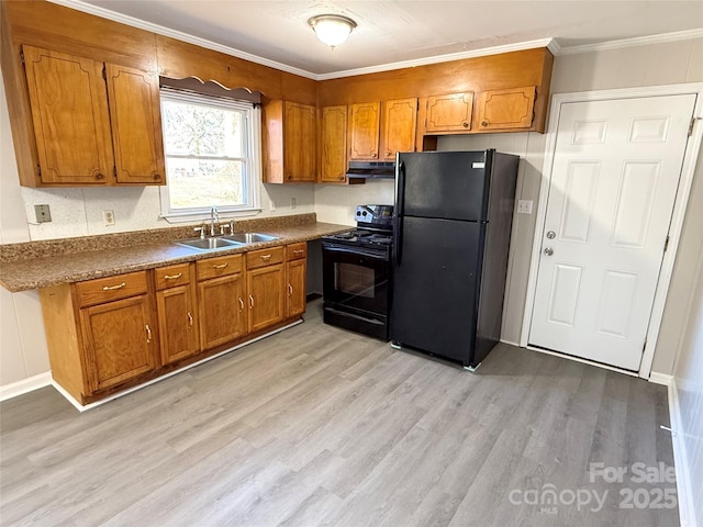 kitchen with dark countertops, light wood-style flooring, brown cabinetry, a sink, and black appliances