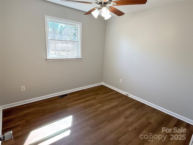 empty room featuring a ceiling fan, visible vents, baseboards, and wood finished floors