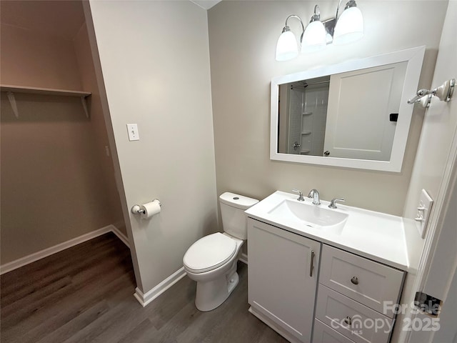 bathroom featuring toilet, wood finished floors, vanity, and baseboards