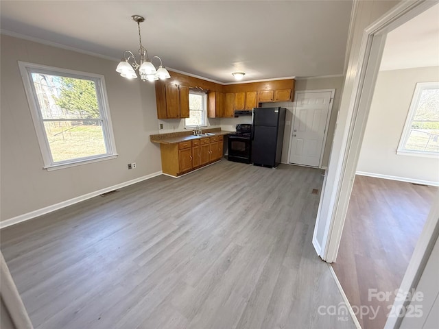 kitchen featuring visible vents, brown cabinetry, decorative light fixtures, light countertops, and black appliances